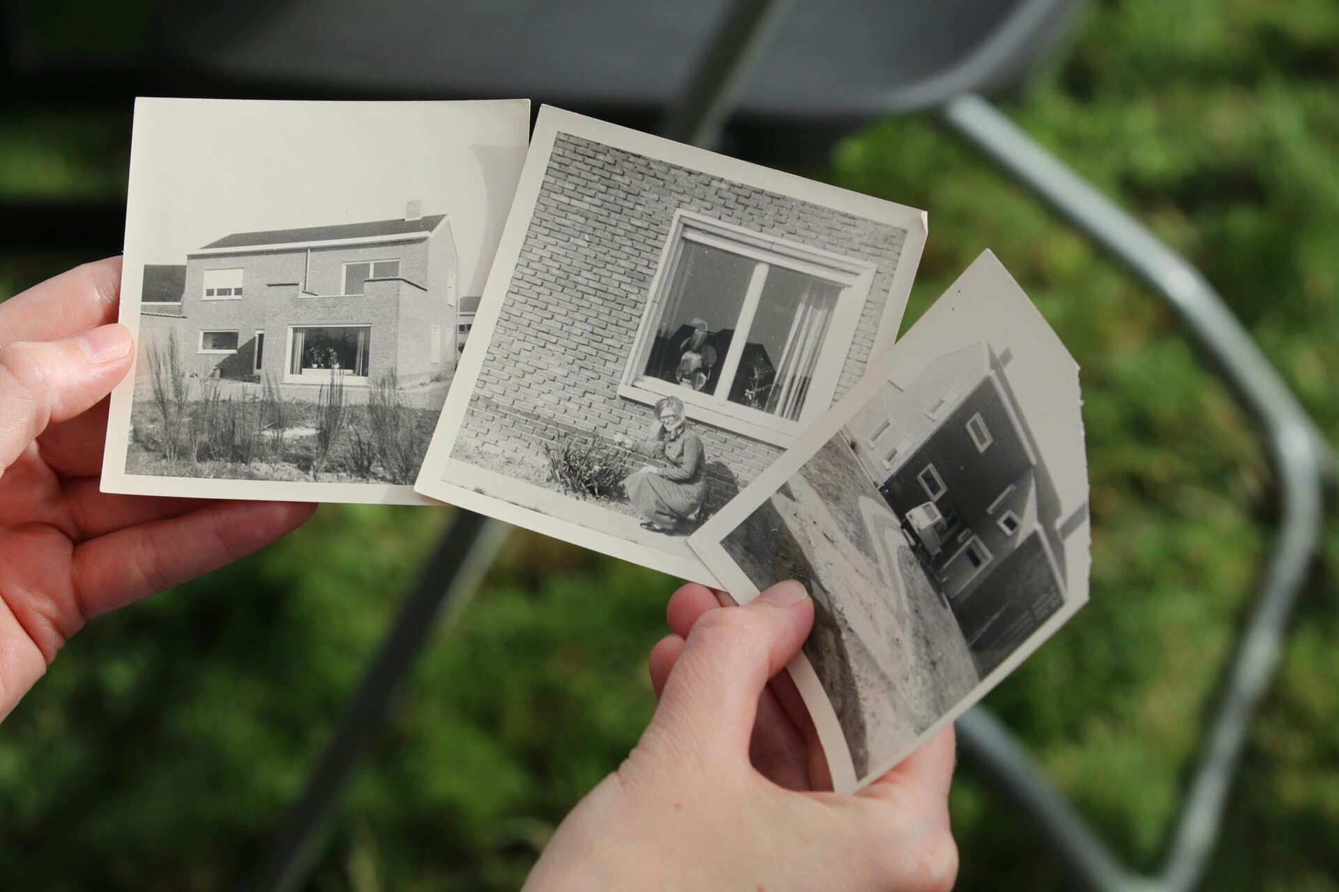 En hand håller i tre gamla svartvita fotografier, ett verktyg för att strukturera sin självbiografi kronologiskt.